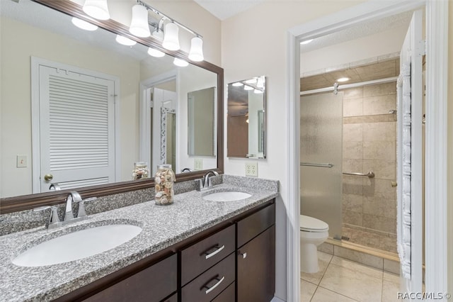 bathroom featuring tile patterned floors, a shower with door, vanity, and toilet