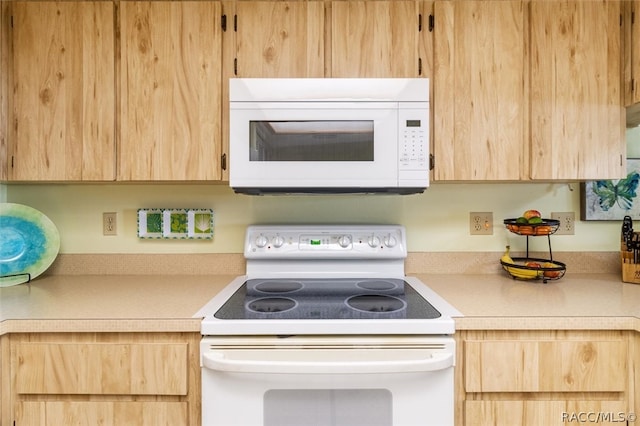 kitchen with light brown cabinetry and white appliances