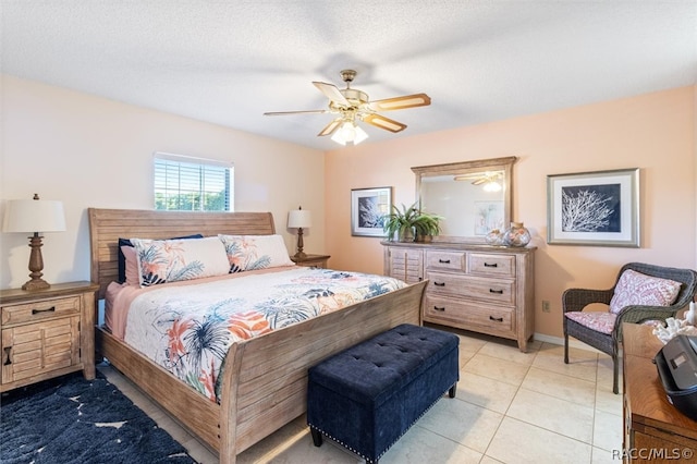 bedroom featuring ceiling fan, light tile patterned floors, and a textured ceiling