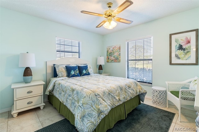 bedroom featuring multiple windows, ceiling fan, light tile patterned flooring, and a textured ceiling