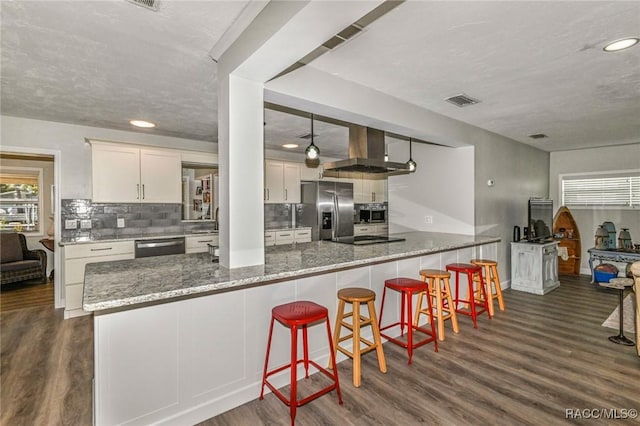 kitchen with stainless steel appliances, dark wood-style flooring, visible vents, wall chimney range hood, and tasteful backsplash