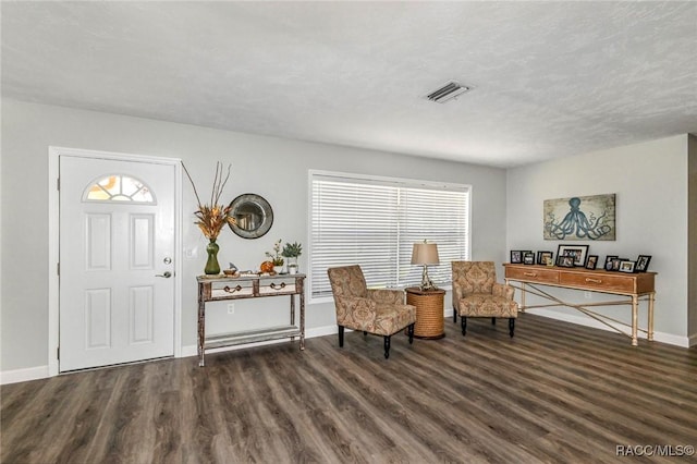 foyer with visible vents, a textured ceiling, baseboards, and wood finished floors