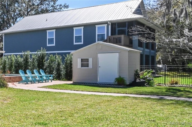 back of property with a yard, a storage shed, metal roof, fence, and an outdoor structure