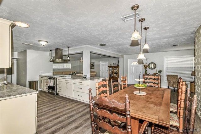 dining area featuring dark wood-style flooring, visible vents, and a textured ceiling