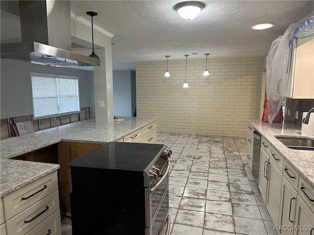 kitchen with hanging light fixtures, appliances with stainless steel finishes, a sink, wall chimney range hood, and light stone countertops