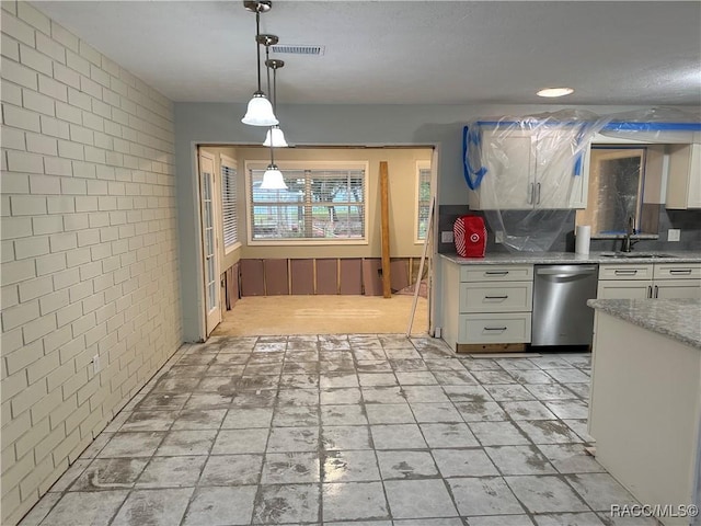 kitchen featuring dishwasher, brick wall, white cabinetry, and a sink