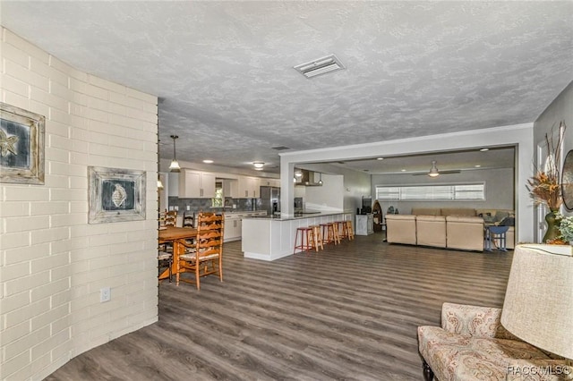 living room with dark wood-style floors, visible vents, a textured ceiling, and a ceiling fan