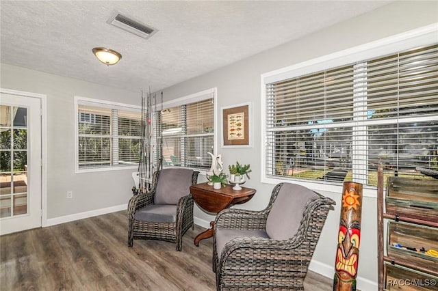 interior space featuring baseboards, a textured ceiling, visible vents, and wood finished floors