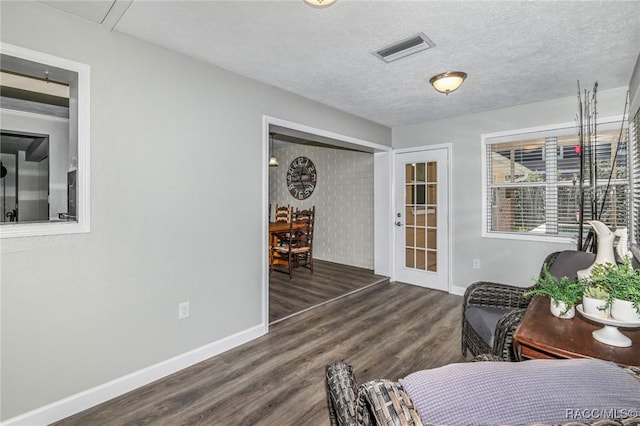 interior space with a textured ceiling, wood finished floors, visible vents, and baseboards