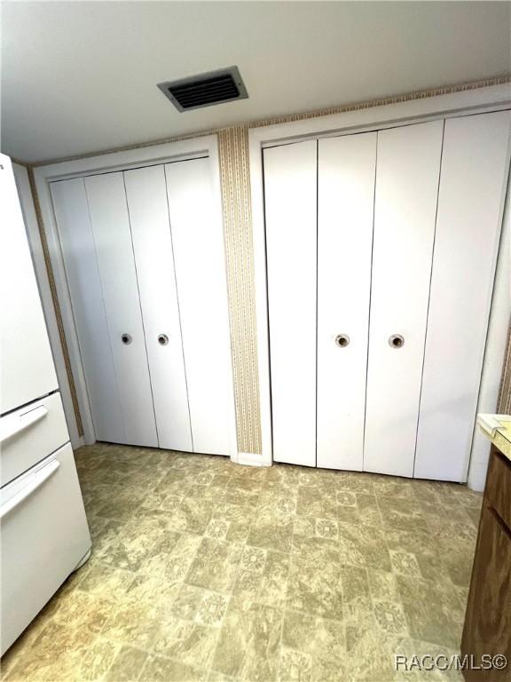 unfurnished bedroom featuring white fridge