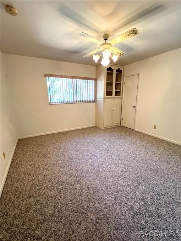 spare room with ceiling fan and carpet