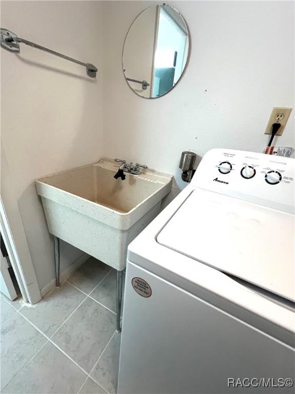 washroom featuring light tile patterned flooring, washer / dryer, and sink