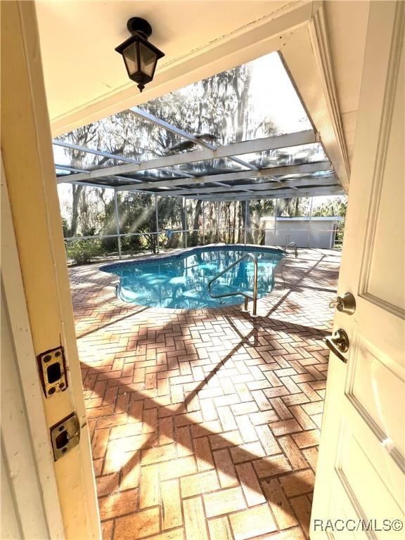 view of swimming pool featuring a patio and glass enclosure