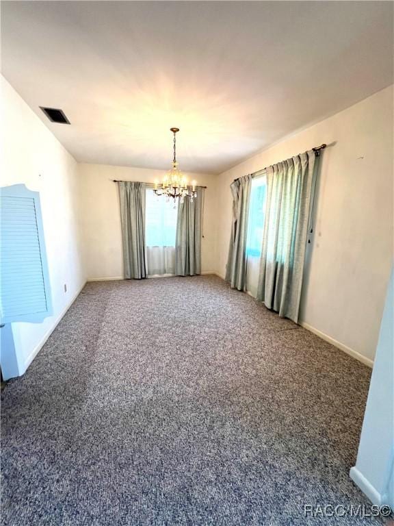 carpeted empty room with a chandelier