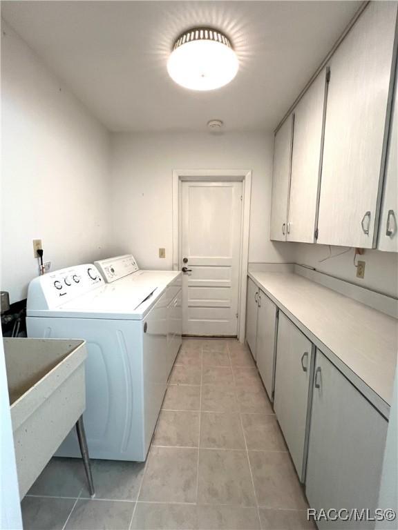 washroom with sink, light tile patterned floors, washer and clothes dryer, and cabinets