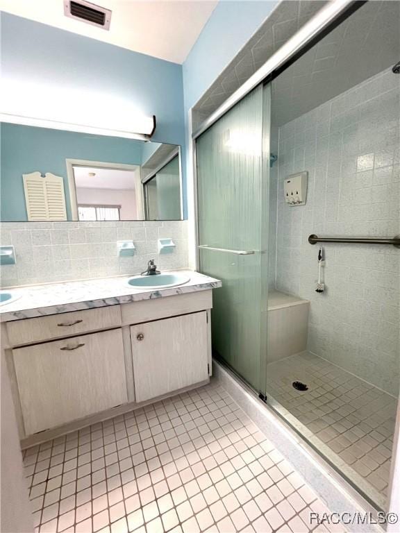 bathroom with vanity, backsplash, tile patterned floors, and an enclosed shower