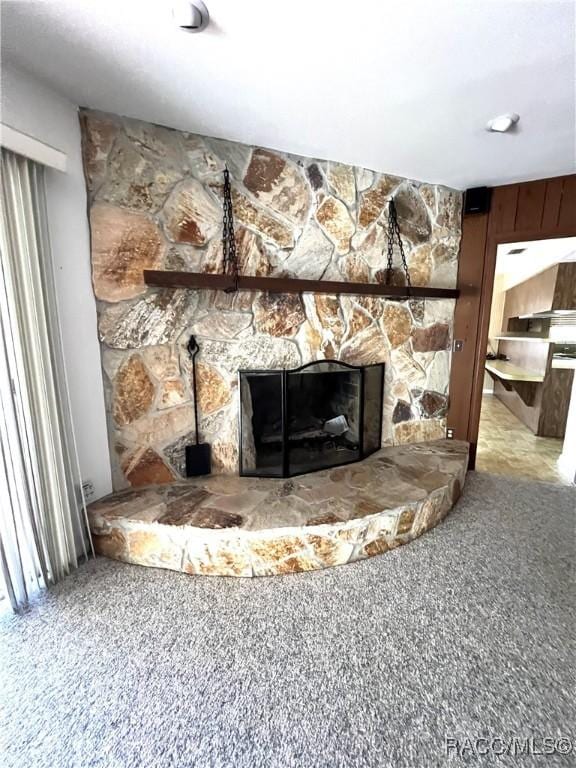 room details featuring a stone fireplace, carpet flooring, and wooden walls