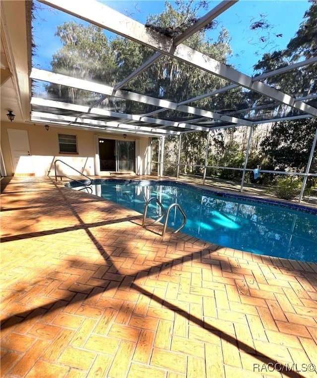 view of swimming pool featuring a patio and glass enclosure