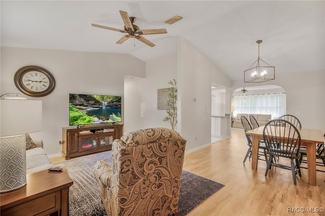 dining space with lofted ceiling, ceiling fan with notable chandelier, visible vents, baseboards, and light wood-type flooring