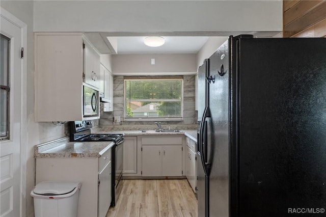833 Maple Ave, Inverness, FL 34452 - kitchen with black appliances, a sink, light countertops, light wood-type flooring, and white cabinets