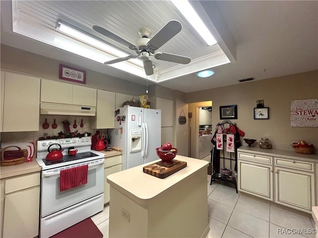 kitchen featuring a tray ceiling, a kitchen island, white appliances, and cream cabinetry