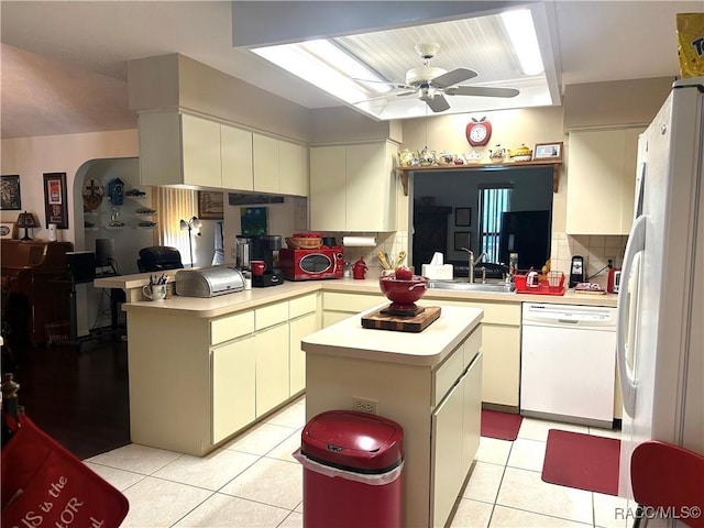 kitchen with a center island, sink, white appliances, and kitchen peninsula