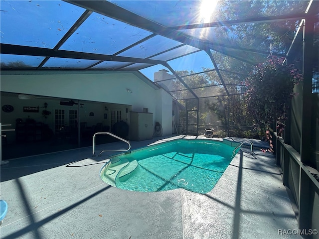 view of pool with glass enclosure, ceiling fan, and a patio area