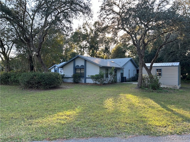 ranch-style home featuring a front yard, a storage unit, and central air condition unit