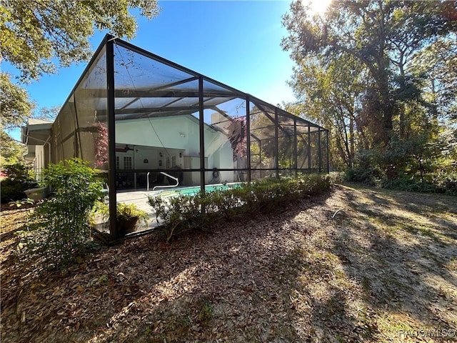 view of yard featuring glass enclosure and ceiling fan