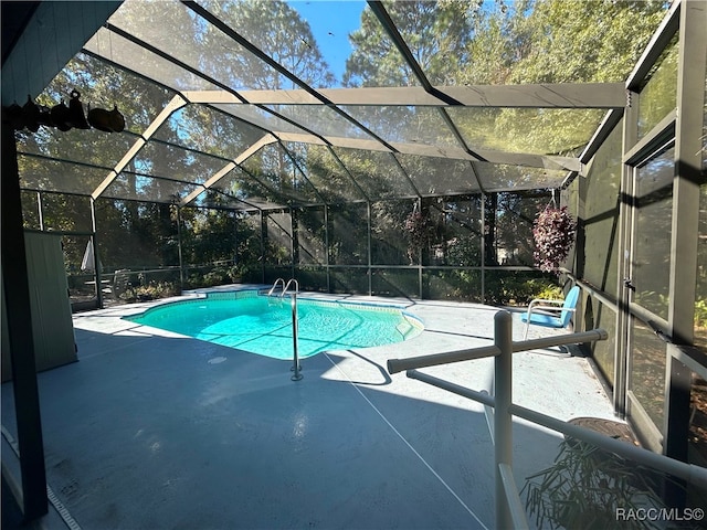 view of swimming pool featuring a patio area and a lanai