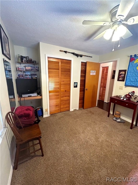 living area with carpet flooring, ceiling fan, and a textured ceiling