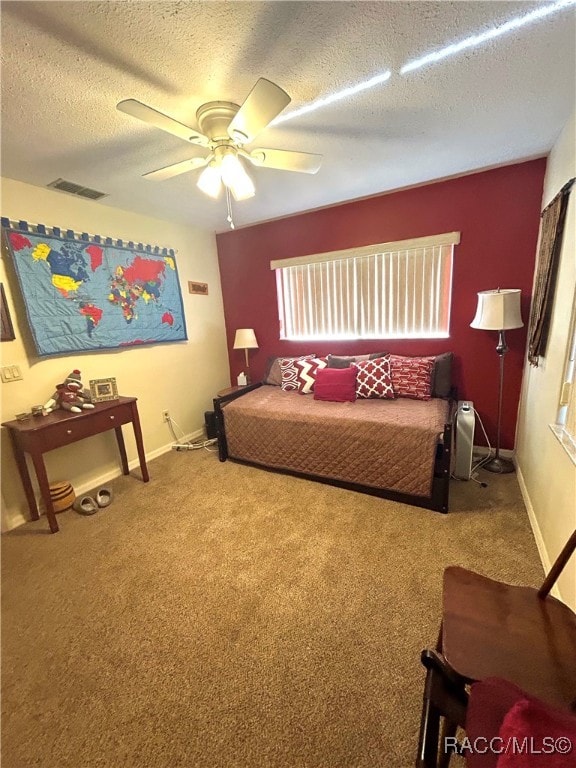 carpeted bedroom with ceiling fan and a textured ceiling