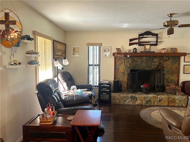 living room featuring ceiling fan, a fireplace, a textured ceiling, and hardwood / wood-style flooring