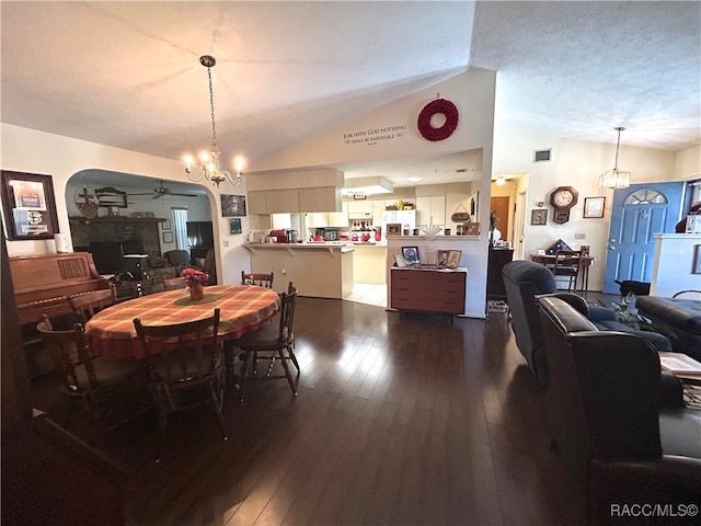 dining space featuring hardwood / wood-style floors, ceiling fan with notable chandelier, a textured ceiling, and vaulted ceiling