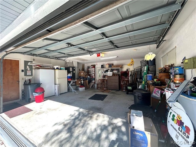 garage featuring electric panel, white fridge, and a garage door opener