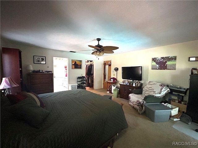 bedroom featuring light carpet, a closet, a spacious closet, and ceiling fan