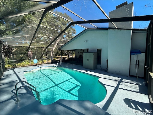 view of pool with glass enclosure and a patio