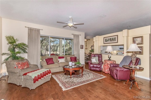 living area with baseboards, a ceiling fan, and wood finished floors