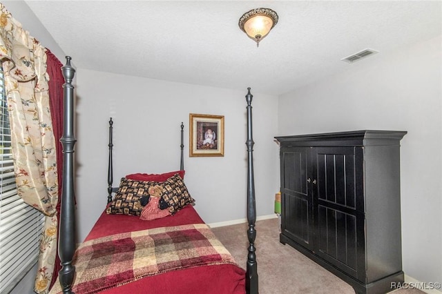 bedroom with carpet, a textured ceiling, visible vents, and baseboards