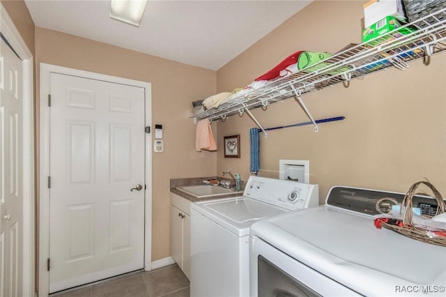 washroom with cabinet space, light tile patterned floors, washer and clothes dryer, and a sink