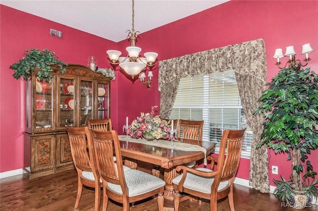 dining area with dark wood-type flooring, visible vents, a notable chandelier, and baseboards