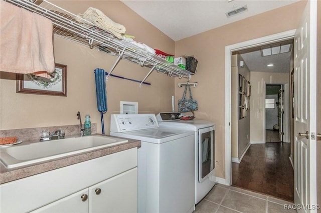 clothes washing area with light tile patterned floors, baseboards, visible vents, separate washer and dryer, and a sink