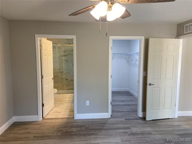 unfurnished bedroom with dark hardwood / wood-style flooring, a spacious closet, a closet, and ensuite bathroom