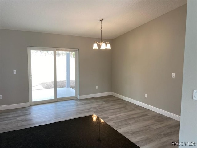 unfurnished room featuring hardwood / wood-style flooring and an inviting chandelier