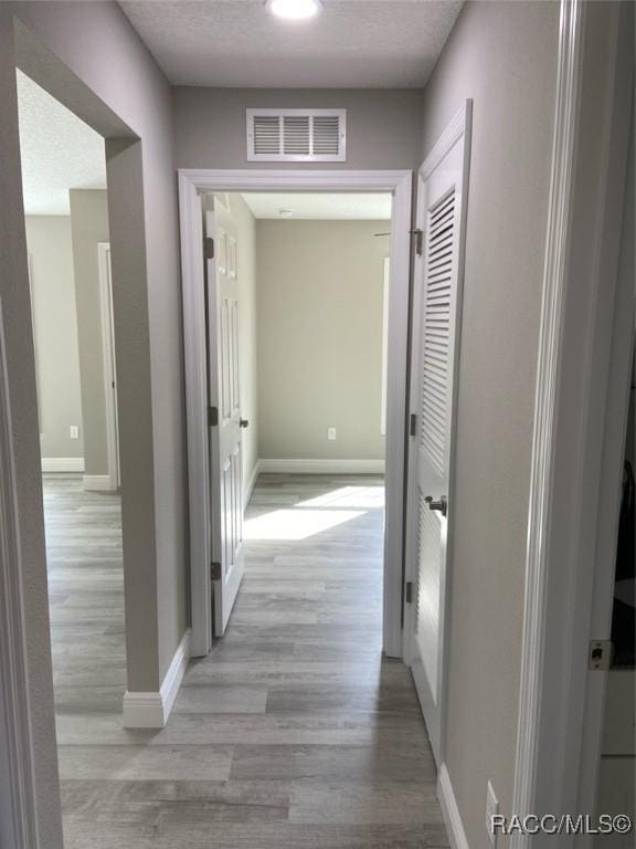 hall featuring a textured ceiling and light wood-type flooring