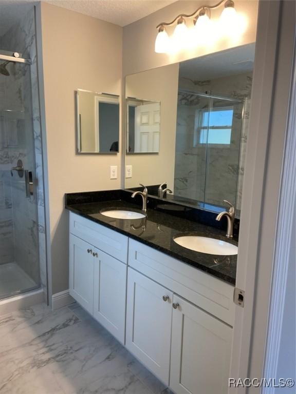 bathroom with walk in shower, vanity, and a textured ceiling