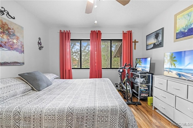 bedroom featuring ceiling fan, light hardwood / wood-style floors, and a textured ceiling