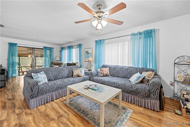 living room featuring a textured ceiling, ceiling fan, and hardwood / wood-style flooring