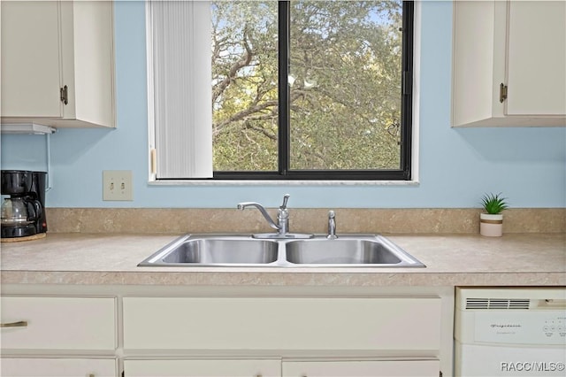 kitchen with sink, white dishwasher, and white cabinetry