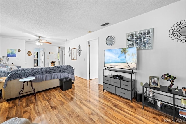 bedroom featuring a textured ceiling, ceiling fan, and light hardwood / wood-style flooring